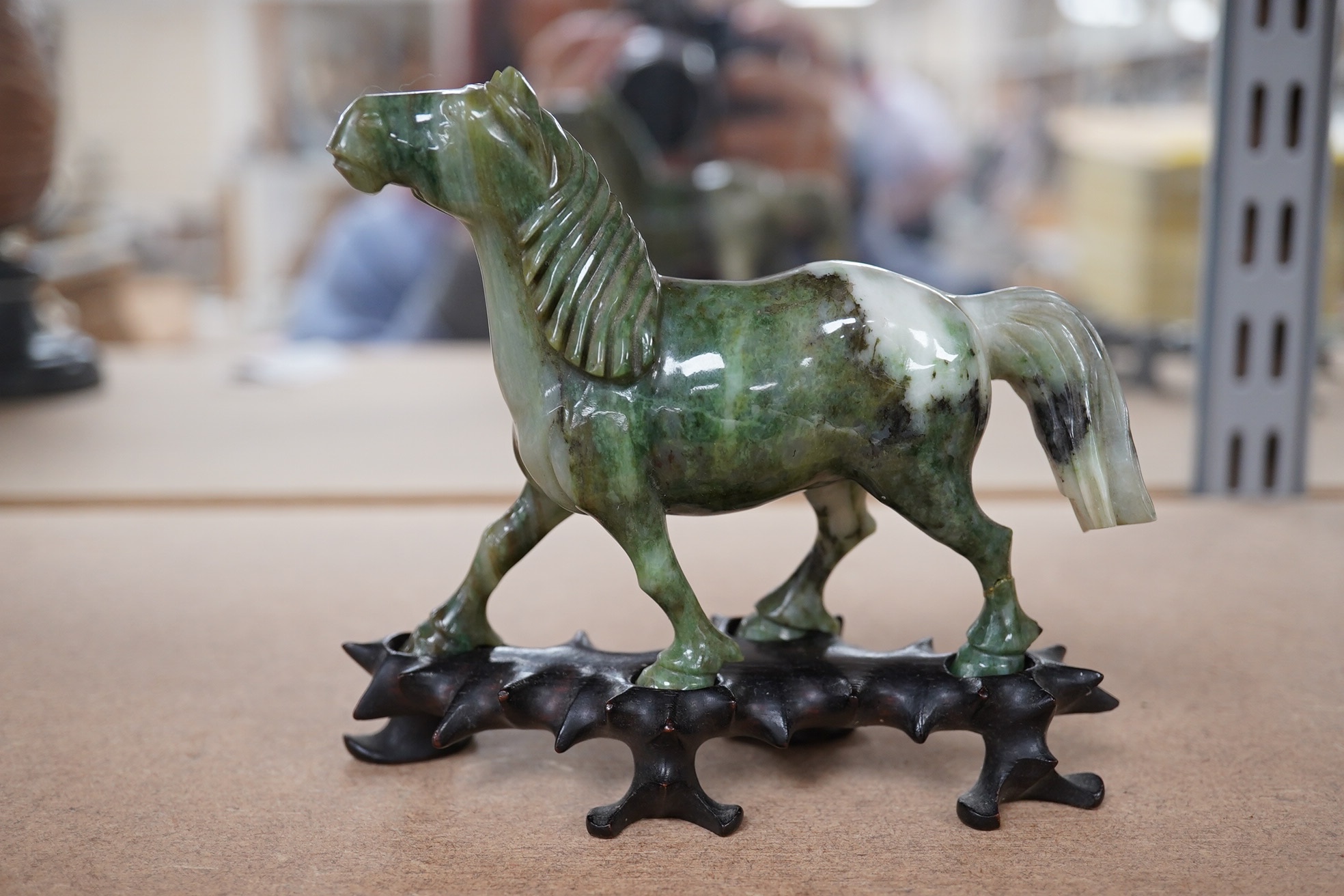 A pair of mid 20th century Chinese jadeite figures of horses, raised on hardwood stands, 13cm wide. Condition - fair, two legs broken and re-glued